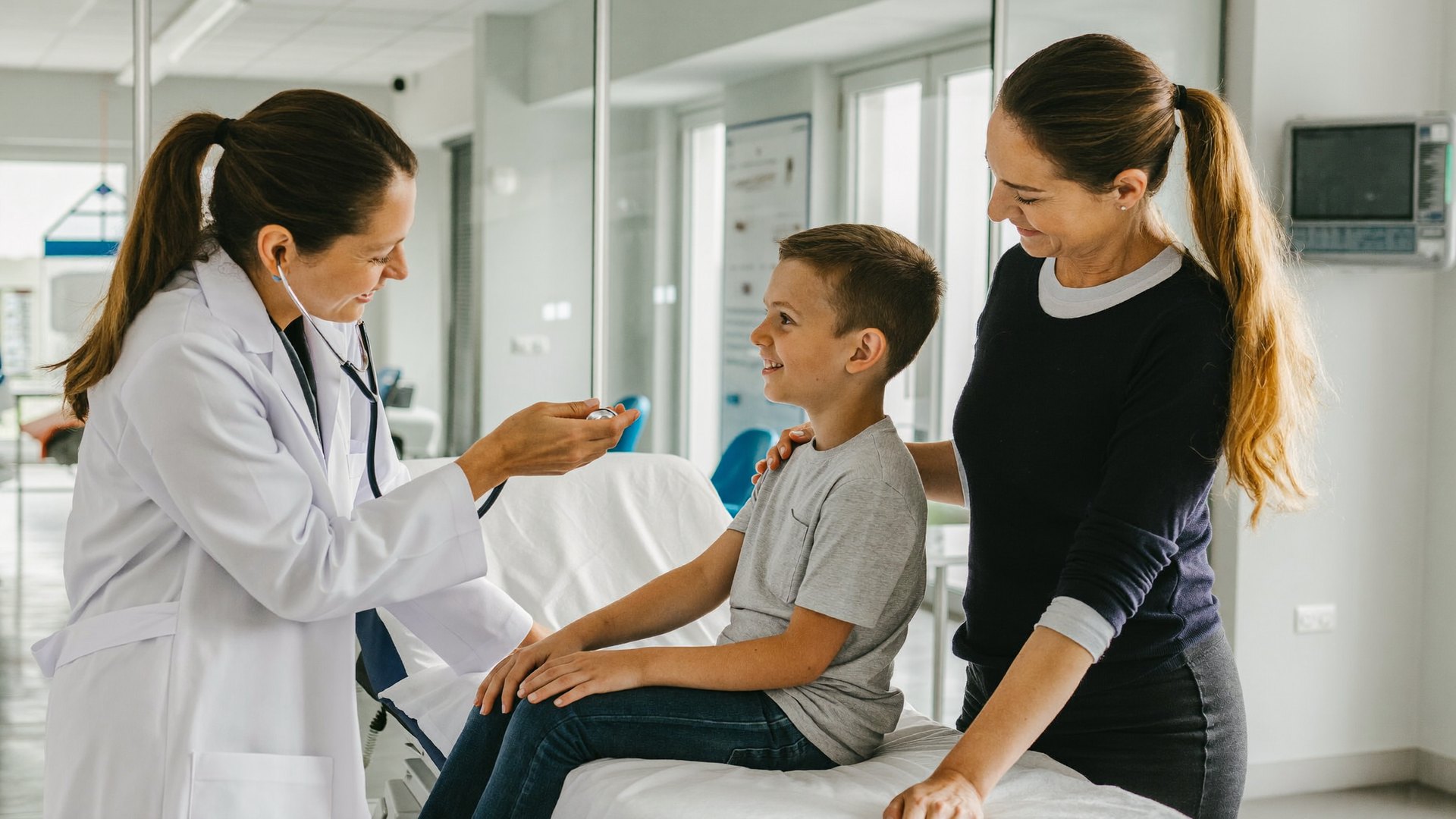 Klinikte bir doktor çocuğu dinliyor, annesi yanında